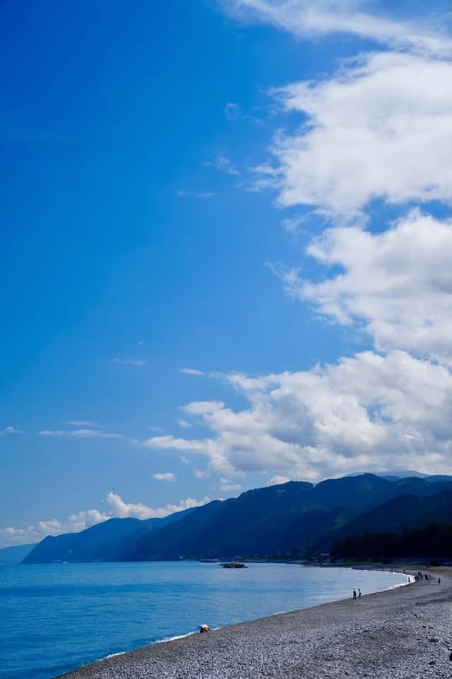朝日町の海岸。青い海に沿って小石の浜が続き、奥に山並みが迫っている